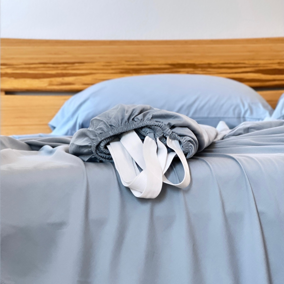 Gray Copper Infused Bamboo Pillowcase Set on blue bedding with wood headboard.